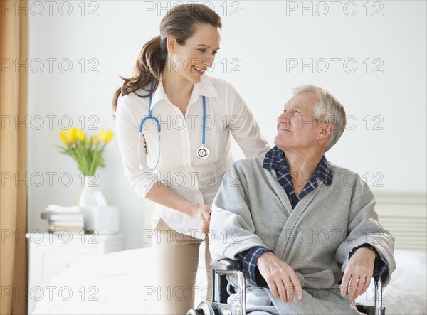 Nurse helping senior man in wheelchair.