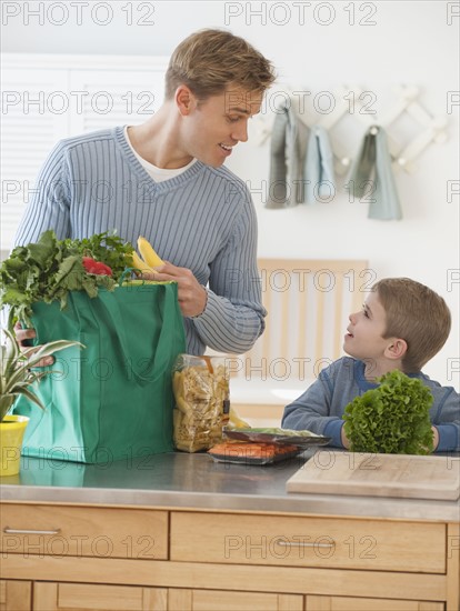 Father and son unpacking groceries.