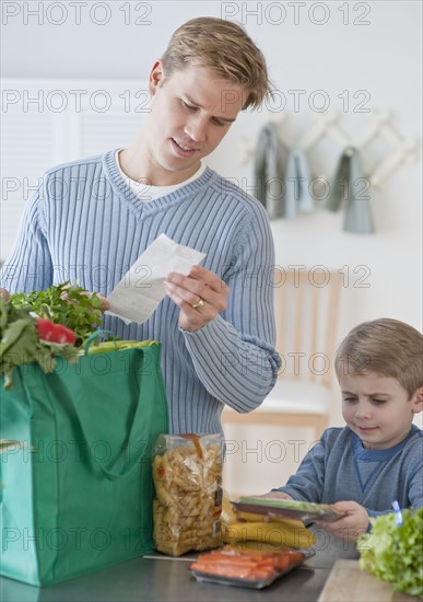 Father and son unpacking groceries.