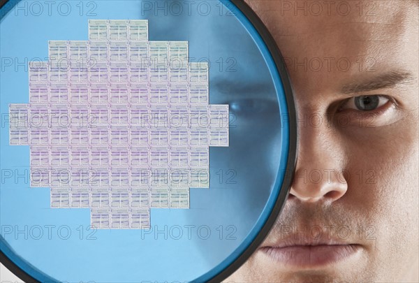 Close up of man looking through computer chip.