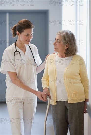 Nurse helping senior woman with cane.