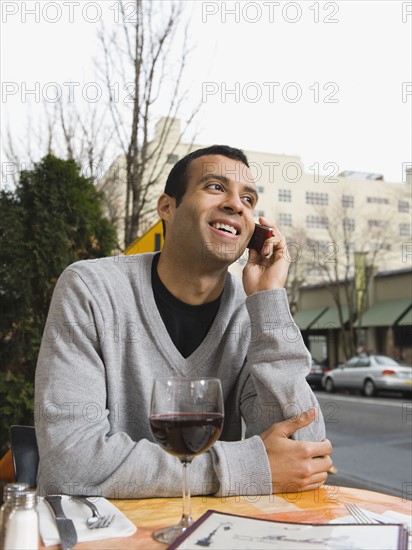 Man talking on cell phone at outdoor cafe.