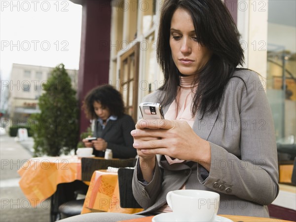 Businesswoman text messaging at outdoor cafe.