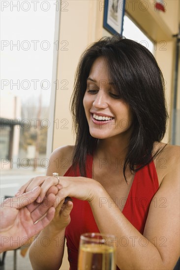 Man giving girlfriend engagement ring in restaurant.