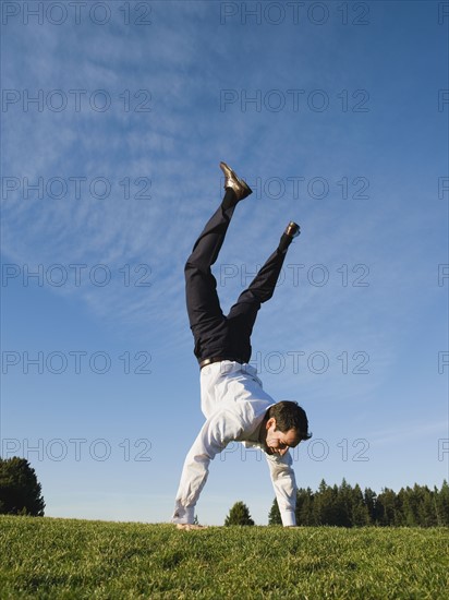 Businessman doing handstand outdoors.