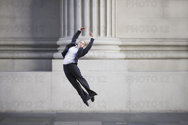 Businesswoman dancing in urban setting. Photographe : PT Images