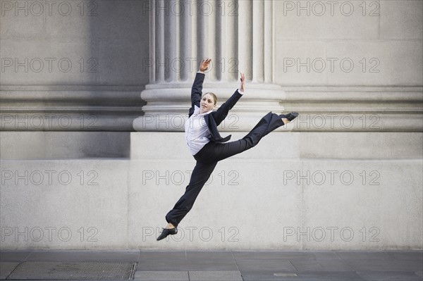 Businesswoman dancing in urban setting. Photographe : PT Images