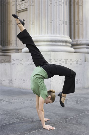 Businesswoman dancing on urban sidewalk. Photographe : PT Images