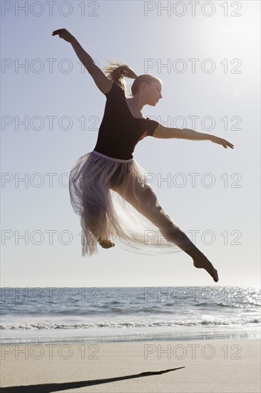 Dancer leaping on beach. Photographe : PT Images