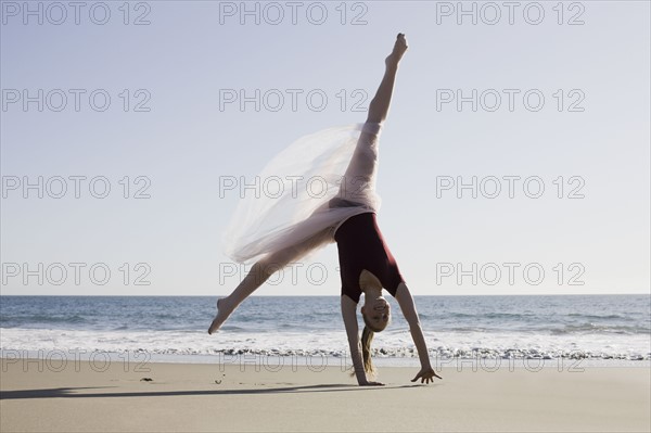 Dancer leaping on beach. Photographe : PT Images