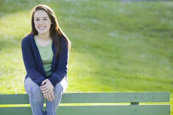 Teenage girl sitting on park bench. Photographe : PT Images