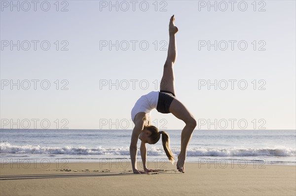 Woman doing yoga on beach. Photographe : PT Images