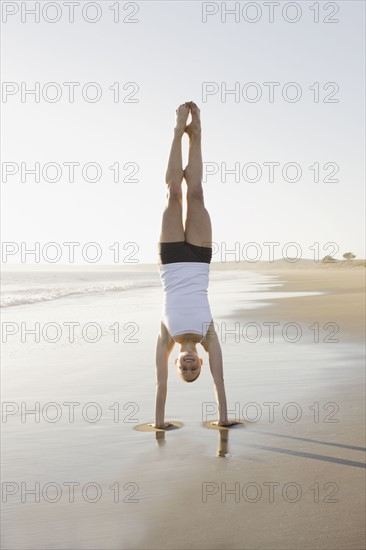 Woman doing yoga on beach. Photographe : PT Images