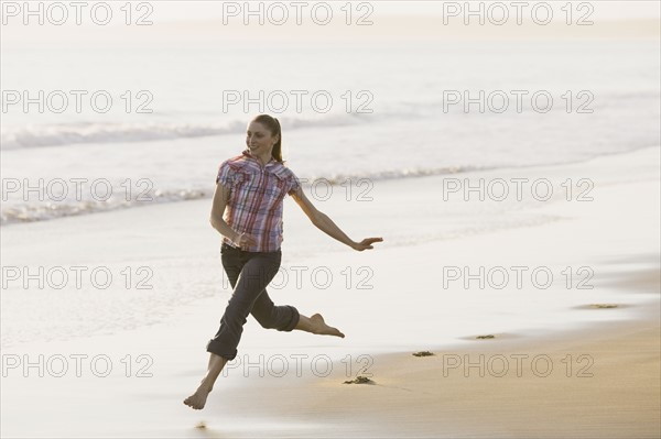 Woman running on beach. Photographe : PT Images