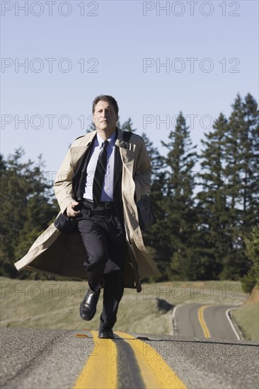 Businessman running on remote road. Photographe : PT Images