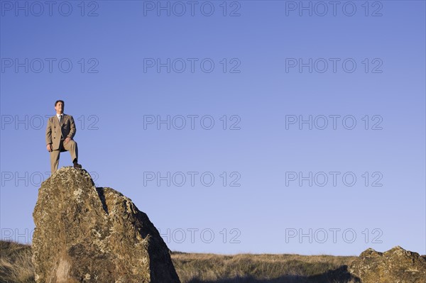 Businessman standing on rock. Photographe : PT Images