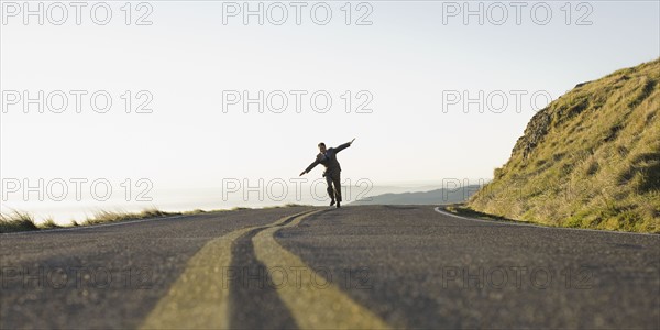 Businessman running on remote road. Photographe : PT Images