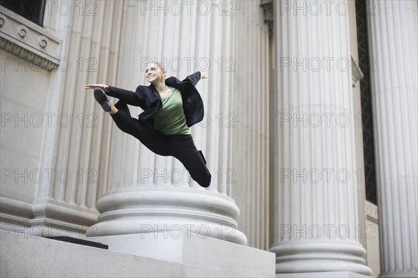 Businesswoman dancing in urban setting. Photographe : PT Images