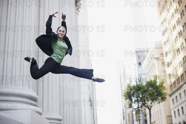 Businesswoman dancing in urban setting. Photographe : PT Images