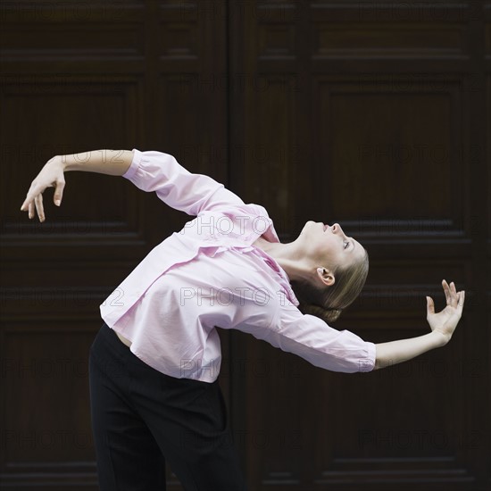 Businesswoman dancing in urban setting. Photographe : PT Images