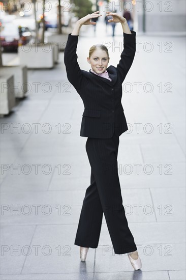 Businesswoman dancing in urban setting. Photographe : PT Images