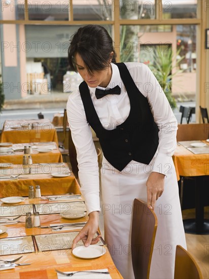 Waitress setting restaurant tables.