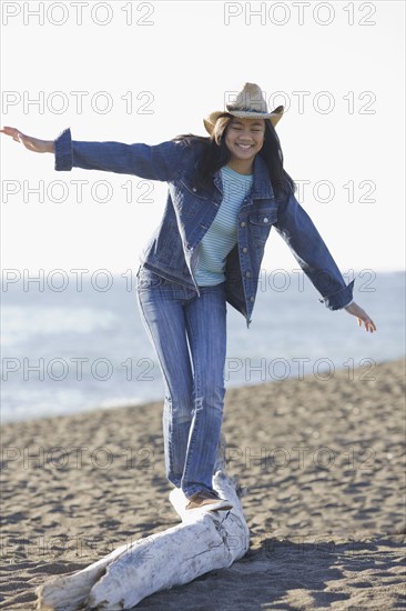 Teenage girl balancing on driftwood. Photographe : PT Images