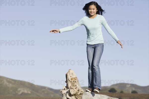 Teenage girl balancing on driftwood. Photographe : PT Images