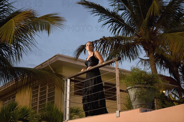 Woman standing on tropical balcony. Photographe : mark edward atkinson