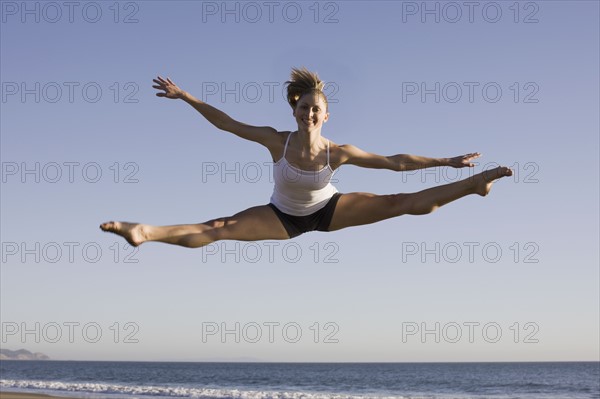 Woman jumping on beach. Photographe : PT Images