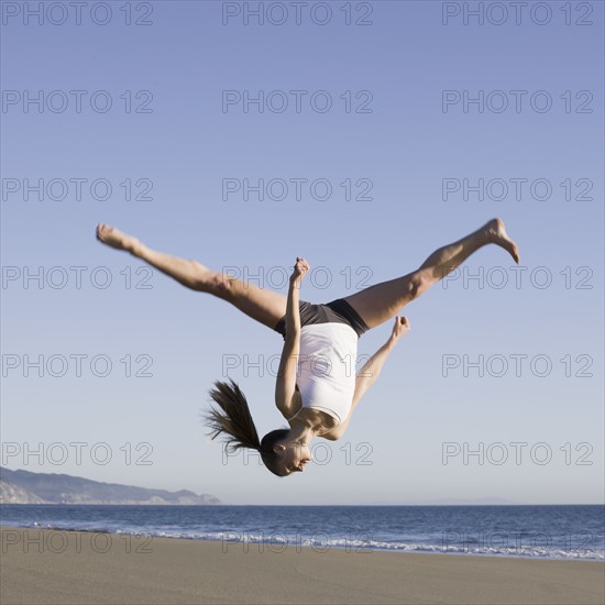 Woman jumping on beach. Photographe : PT Images
