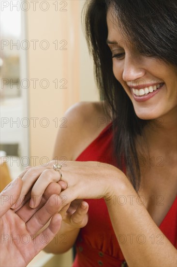 Man giving girlfriend engagement ring in restaurant.