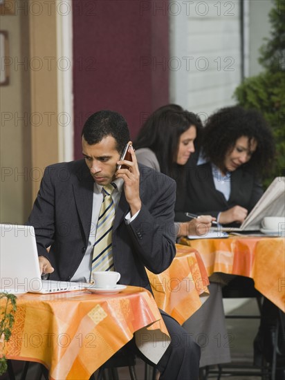 Businessman looking at laptop at outdoor cafe.