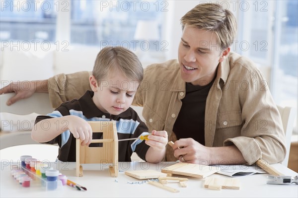 Father and son building wooden model.