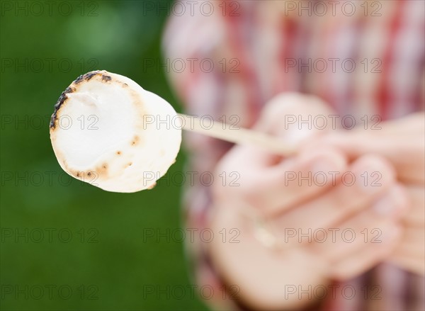 Boy holding roasted marshmallow. Photographe : Jamie Grill