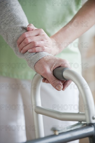 Nurse helping senior woman in walker.