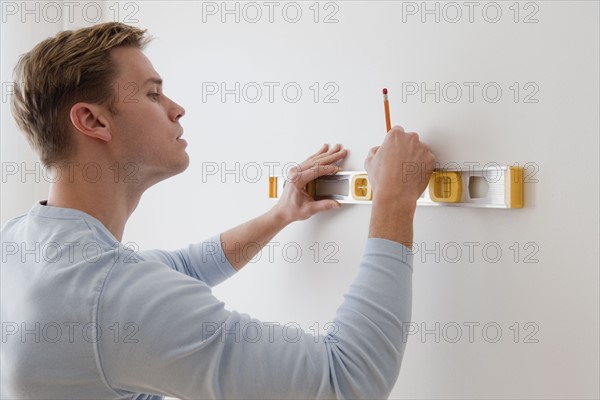 Man marking on wall with level.