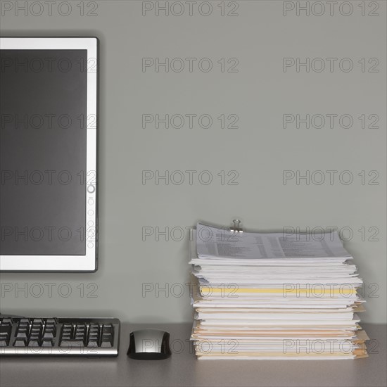 Computer and stack of paperwork.