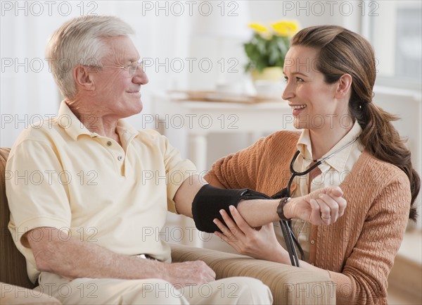 Nurse taking senior man’s blood pressure.