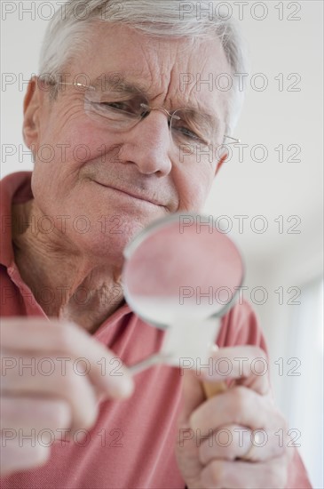 Senior man looking at stamp collection.