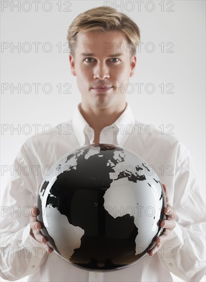 Businessman holding black and white globe.