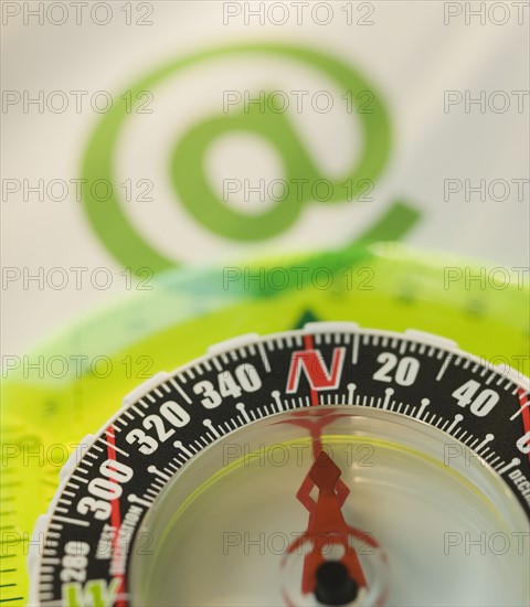 Close up of compass and “at” symbol.