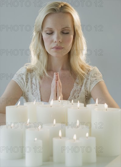 Woman meditating with candles.