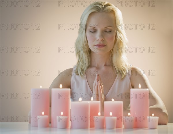 Woman meditating with candles.