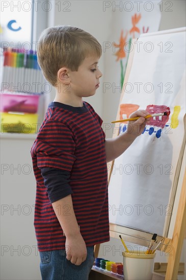 Boy painting on easel.