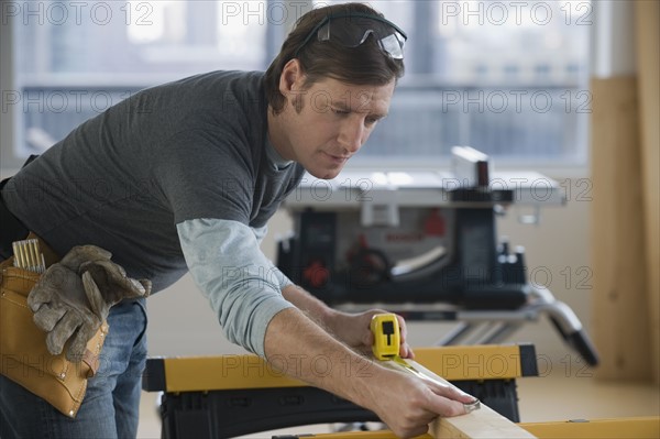 Construction worker measuring board.