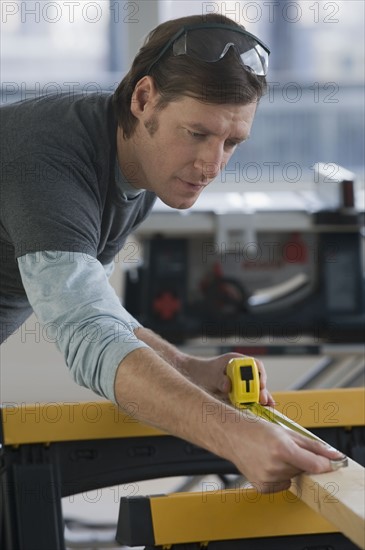 Construction worker measuring board.