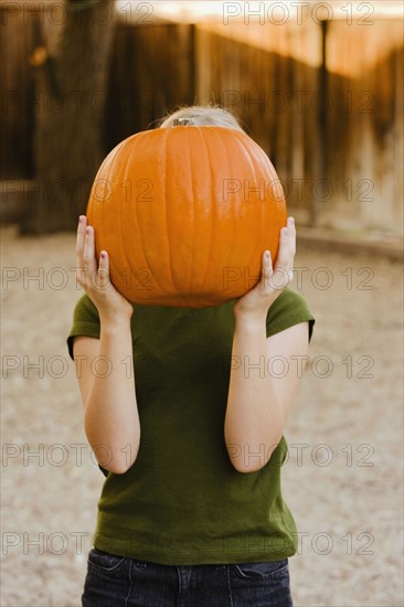 Girl holding pumkin over face