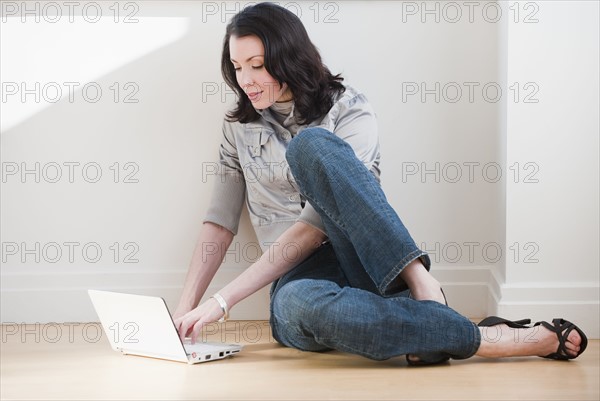 Woman using laptop on floor.