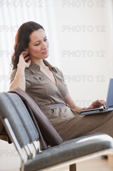 Businesswoman using laptop in waiting room.